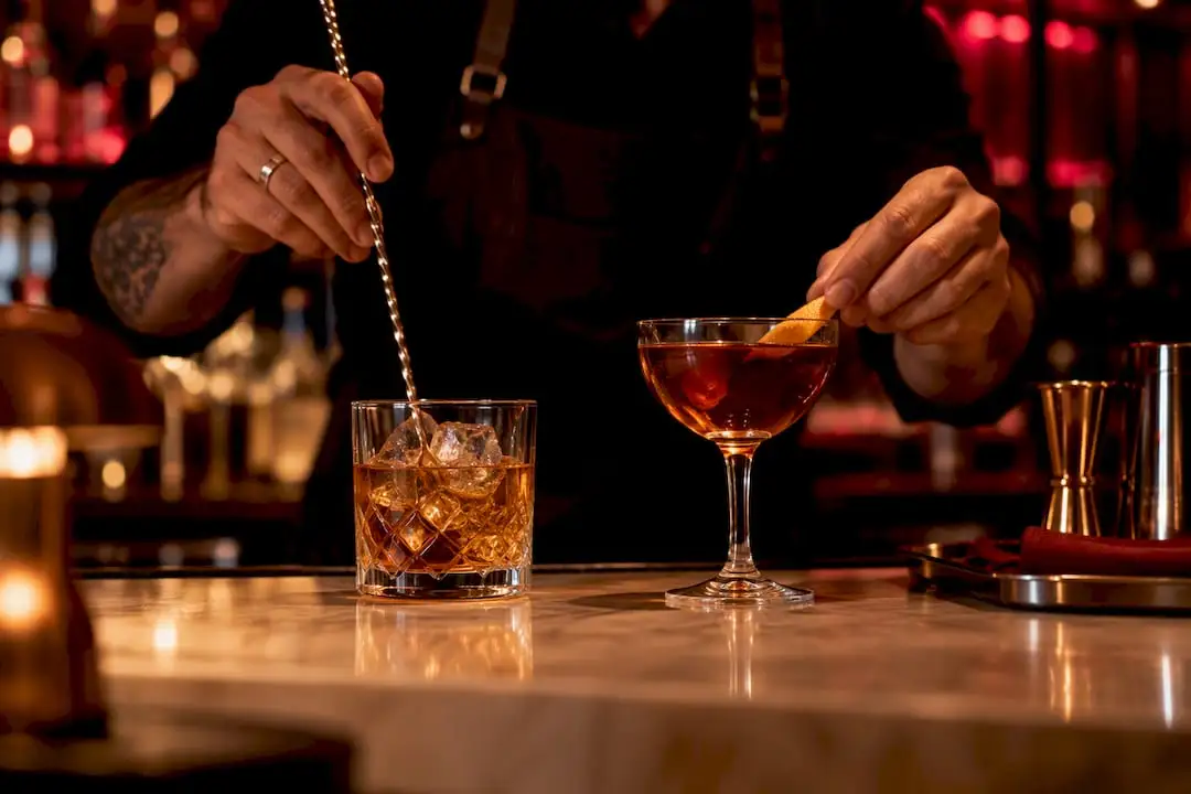 Barman przygotowuje dwa koktajle z whisky
