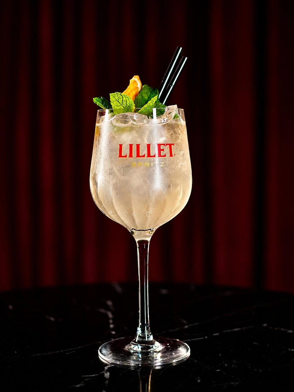 Spritz z lodem w kieliszku z nadrukiem Lillet, z miętą i plasterkiem pomarańczy